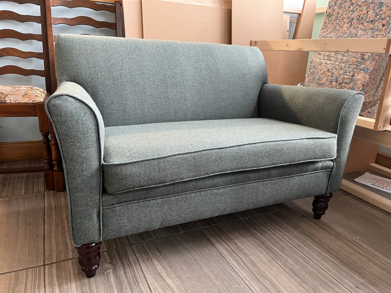 Grey two-seat sofa with dark piping and wooden feet