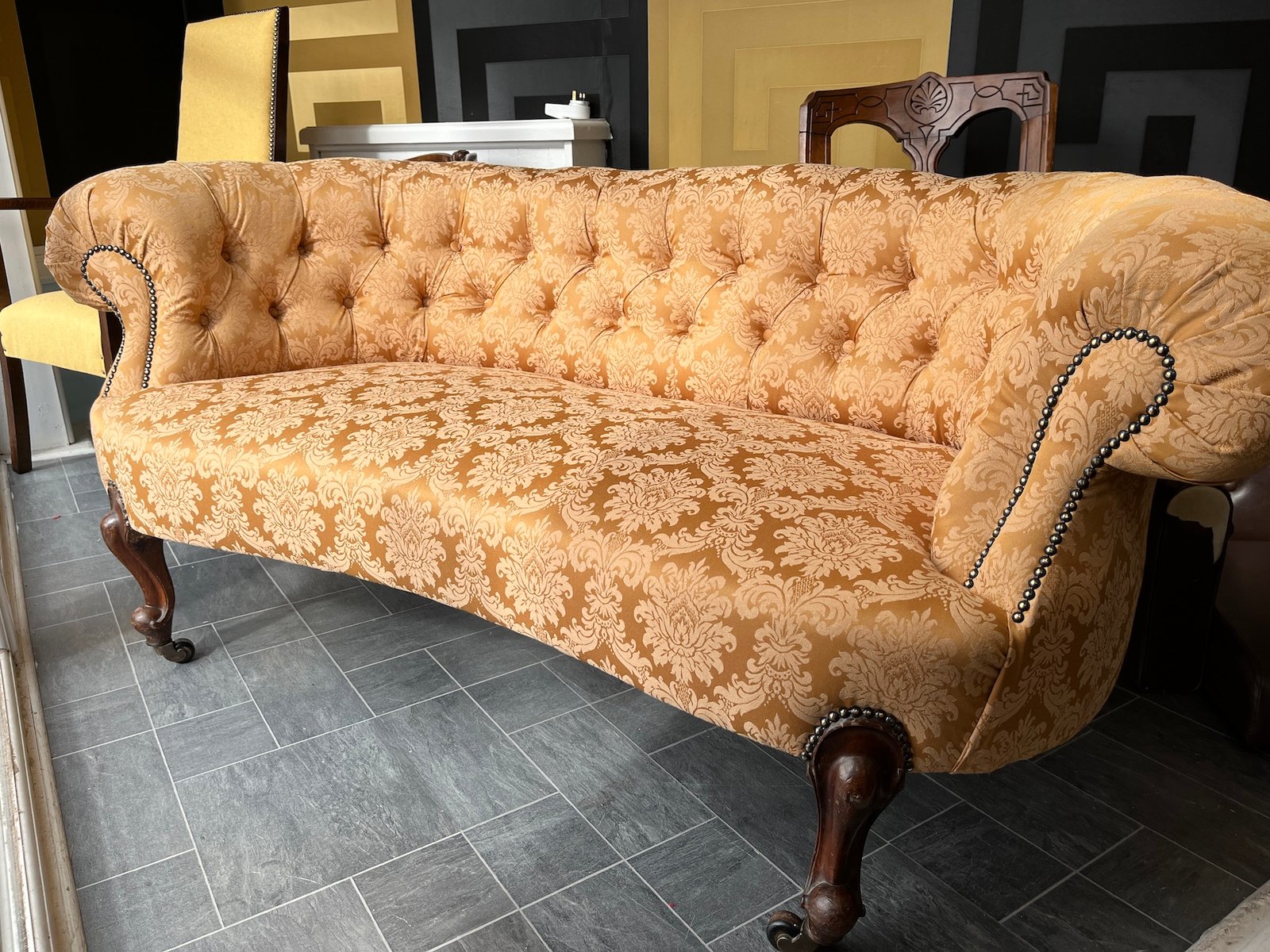 Antique buttoned settee in light patterned upholstery