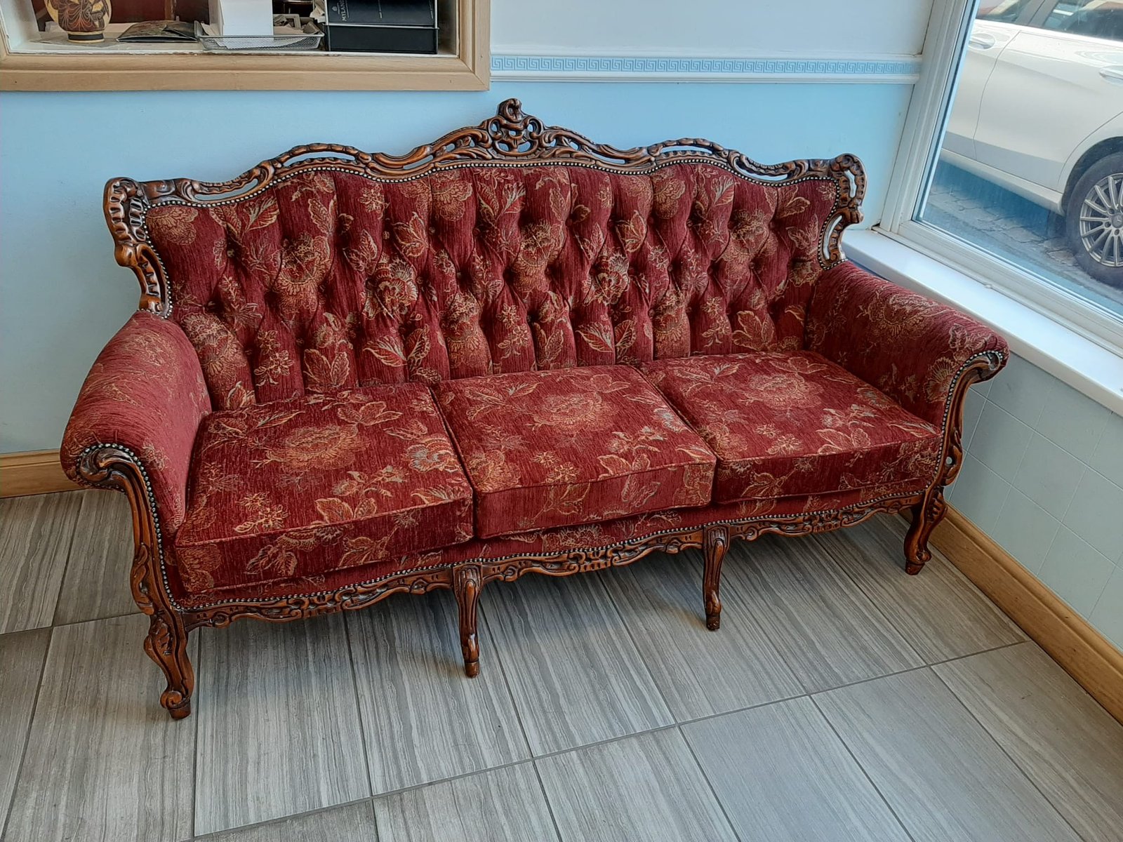 Red buttoned antique settee with carved wooden frame