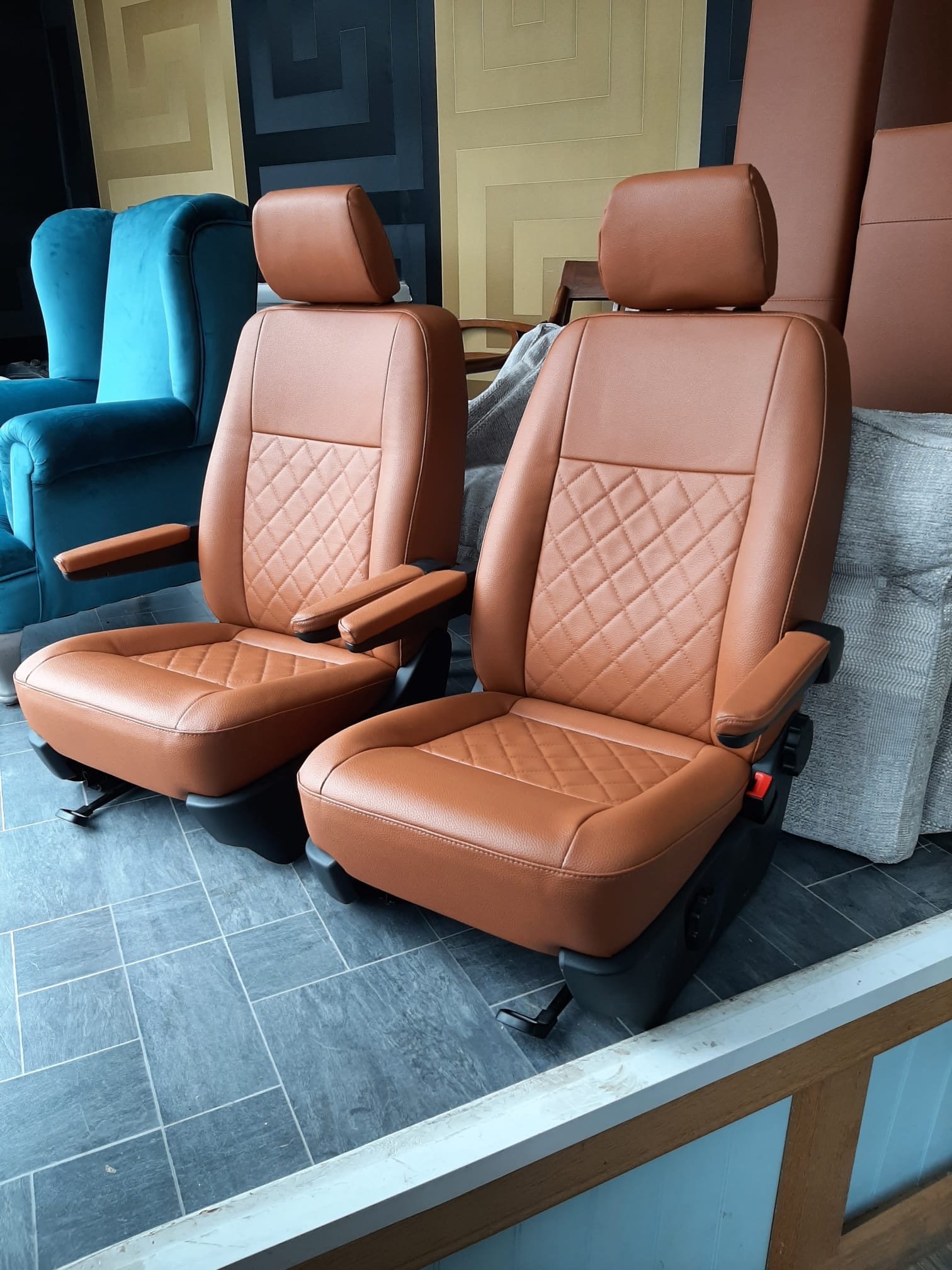 Pair of tan leather vehicle front seats in workshop