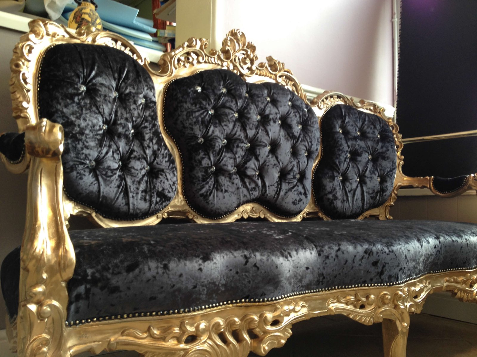Finished ornate gold-and-black antique chaise with buttoned back