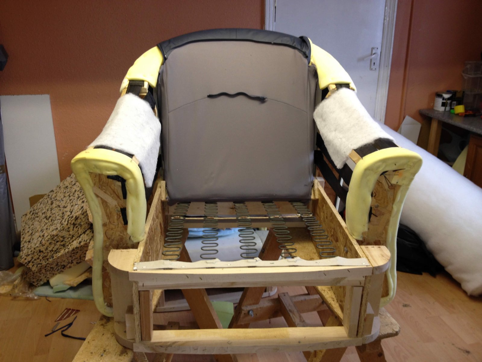 Armchair stripped to a wooden frame mid-repair in the workshop